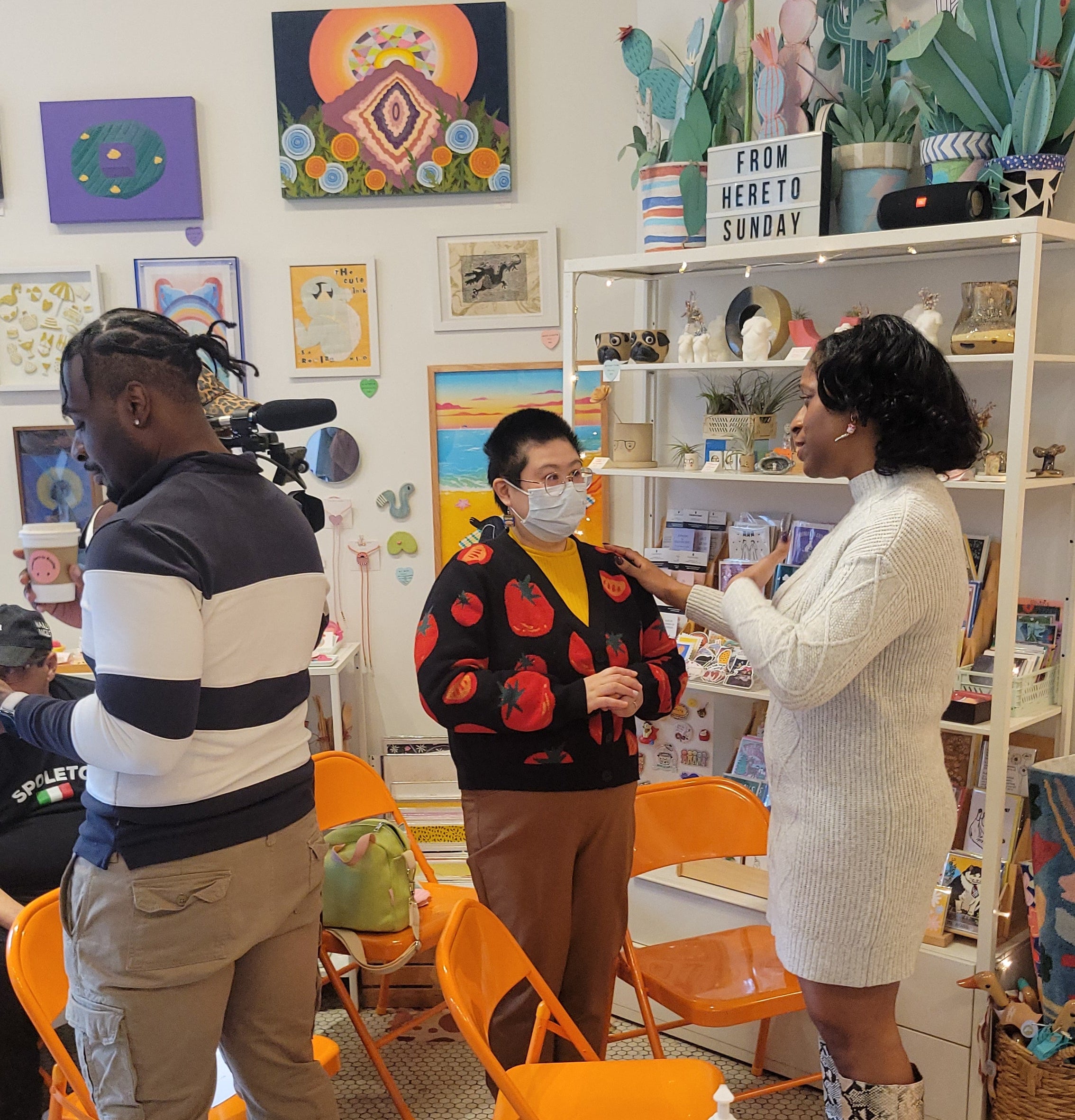 People in a shop with colorful artwork on the walls.
