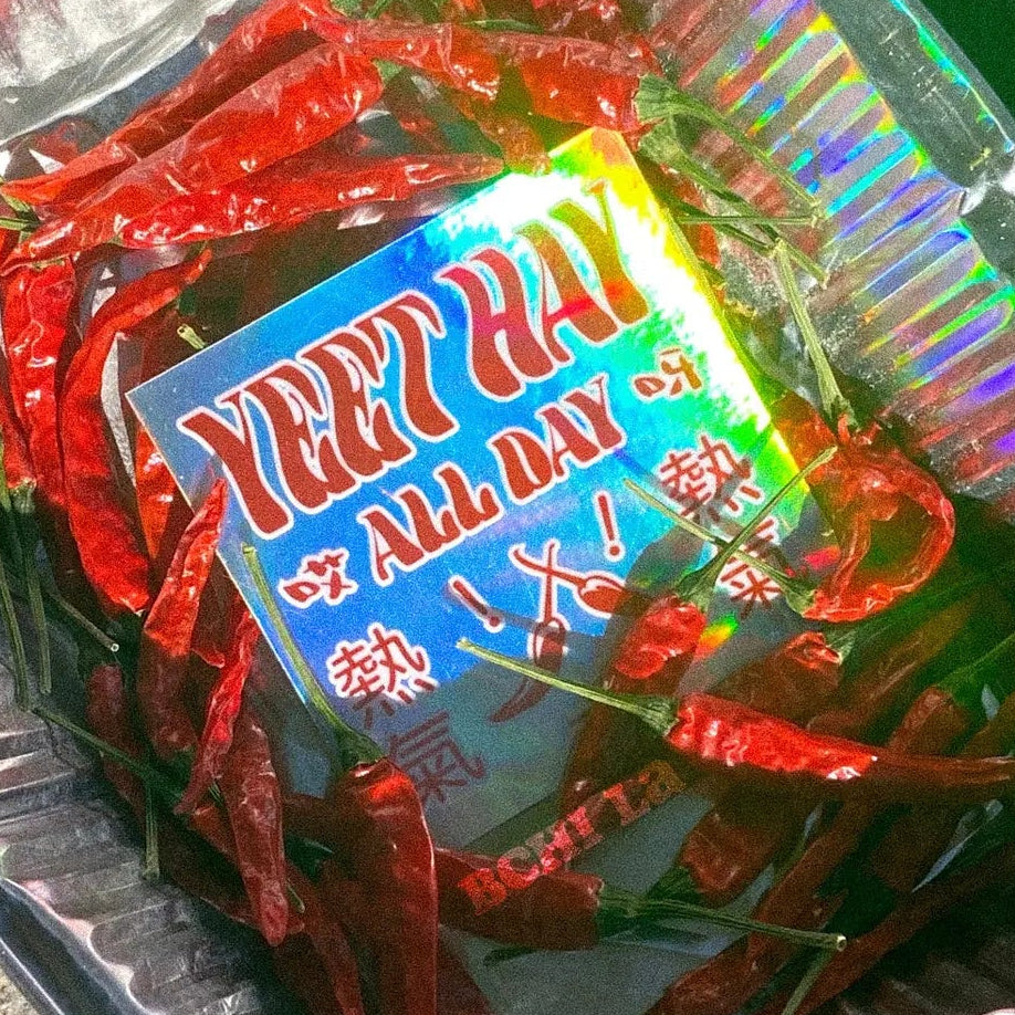 Red chili peppers with a holographic 'Yeet Hay' sticker in an alumimum pan