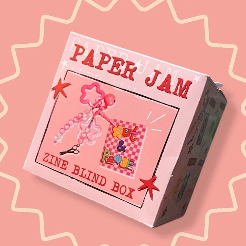 Zine blind box packaging with 'Paper Jam' branding on a pink background