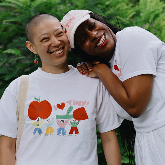 Two people wearing white t-shirts with colorful graphics against a green background