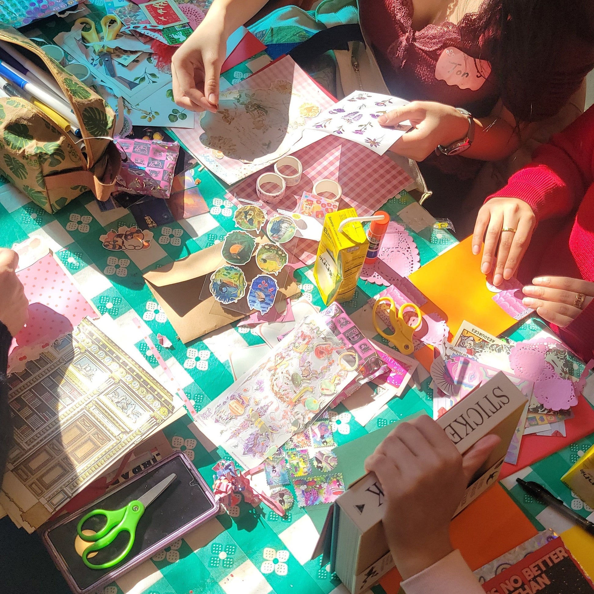 Cropped photo of folks junk journaling with stickers on a colorful table