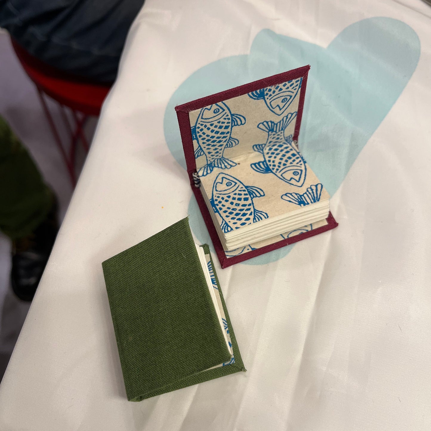 Two tiny handmade books with fish illustrations on a white surface