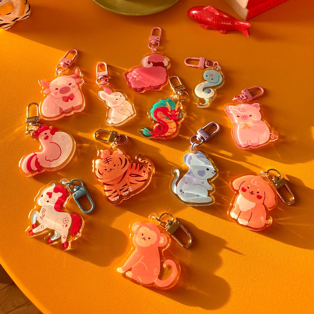Collection of colorful animal-shaped keychains on a yellow surface with decorative items in the background.